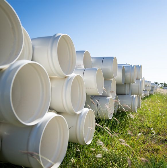 Stacked pipe sitting in grass outside